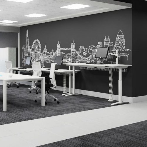 Sit stand desks in an office with some lower desks with chairs and some higher desks with no chairs